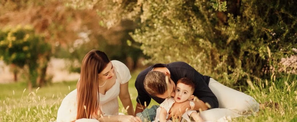 A happy family having a picnic in a lush green park setting during the day.