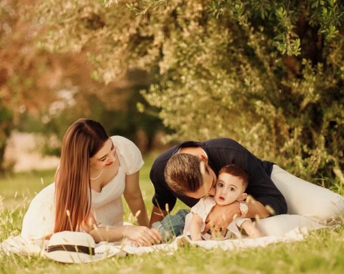 A happy family having a picnic in a lush green park setting during the day.